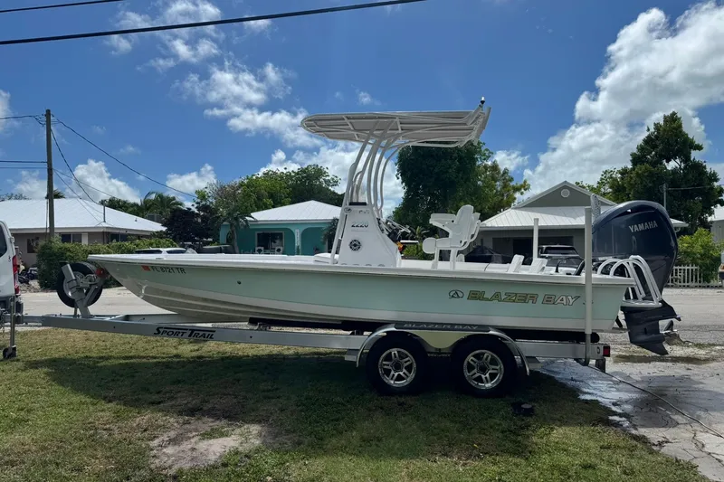 The Image of 2024 Blazer Bay 2220 Fisherman boat on trailer, parked outdoors under a clear blue sky. - 0