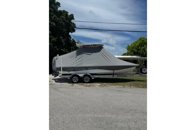 Slide: The Image of 2024 Blazer Bay 2220 Fisherman boat covered on trailer, parked outdoors. - 8