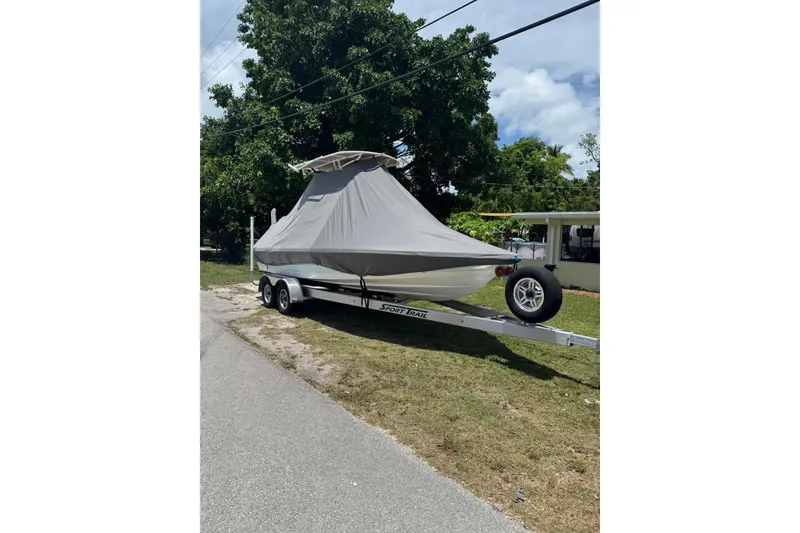 Slide: The Image of 2024 Blazer Bay 2220 Fisherman boat covered on trailer, parked roadside. - 9