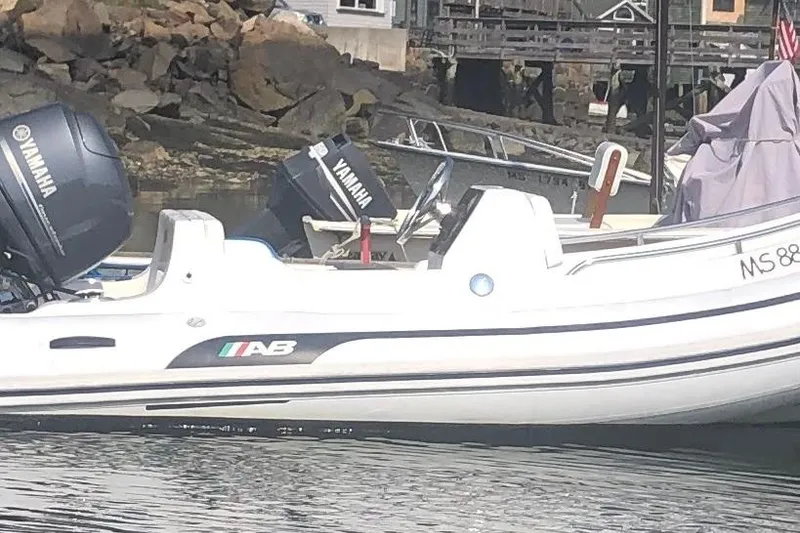The Image of 2010 AB Inflatables Nautilus 13 DLX boat with Yamaha outboard motor docked by rocky shore. - 2