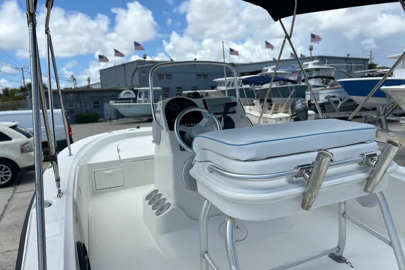 Slide: The Image of 2004 HYDRASPORT 20 boat interior with steering console and seating, docked under a blue sky. - 2