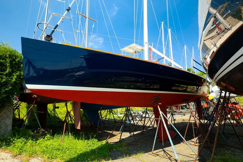 Slide: The Image of 2008 J Boats J/100 sailboat on stands, blue hull, red bottom, sunny day. - 24