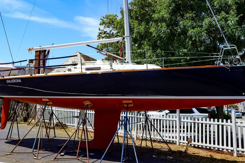 The Image of 2008 J Boats J/100 sailboat on stands, black hull, red bottom, outdoor setting. - 0