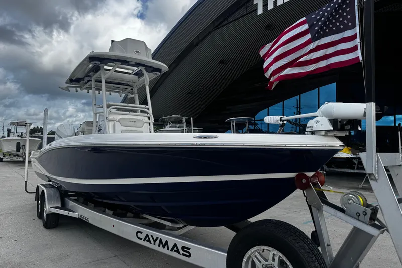 Slide: The Image of 2021 Caymas 28 HB boat on trailer with American flag, parked outdoors. - 2