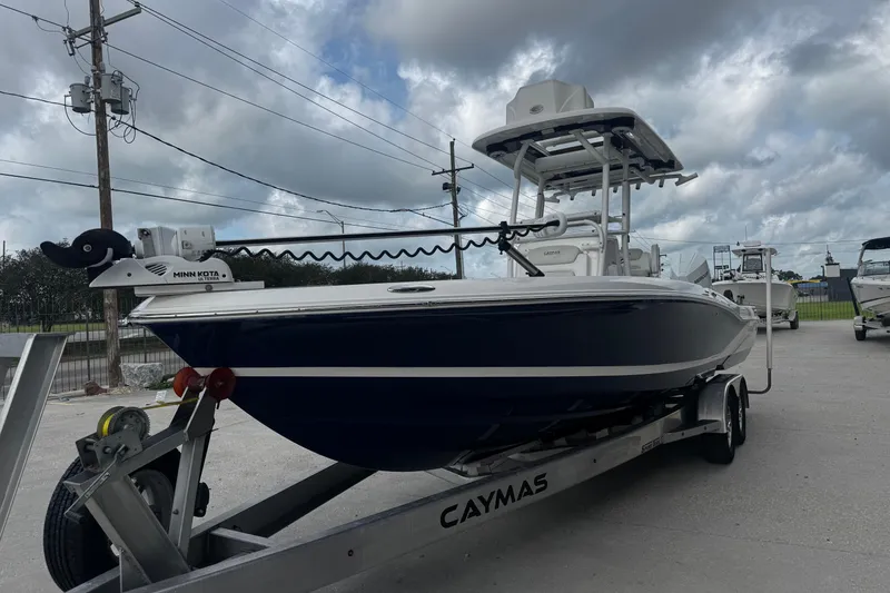 Slide: The Image of 2021 Caymas 28 HB boat on trailer under cloudy sky, featuring Minn Kota motor. - 8
