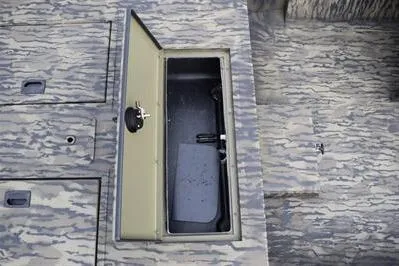 Slide: The Image of 2025 Lowe Roughneck 1860SC boat storage compartment with open lid on camo-patterned deck. - 11