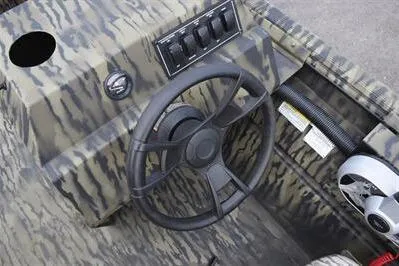 Slide: The Image of 2025 Lowe Roughneck 1860SC boat dashboard with camouflage design and steering wheel. - 16