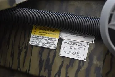 Slide: The Image of 2025 Lowe Roughneck 1860SC boat interior with safety and seating labels, camo design. - 19