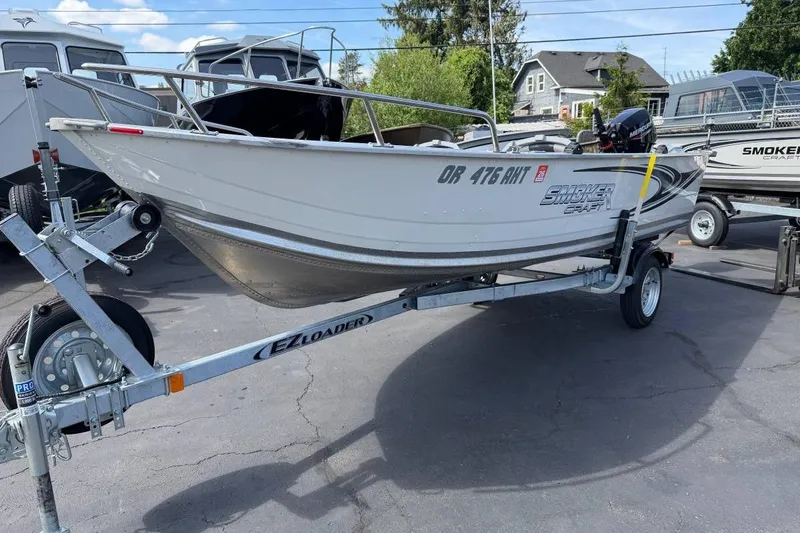 Slide: The Image of 2023 Smoker Craft Alaskan 15 boat on EZ Loader trailer in outdoor setting. - 2