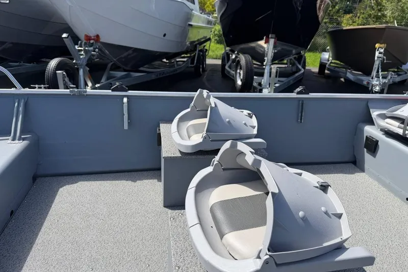 Slide: The Image of 2023 Smoker Craft Alaskan 15 boat interior with seating and trailers in background. - 9