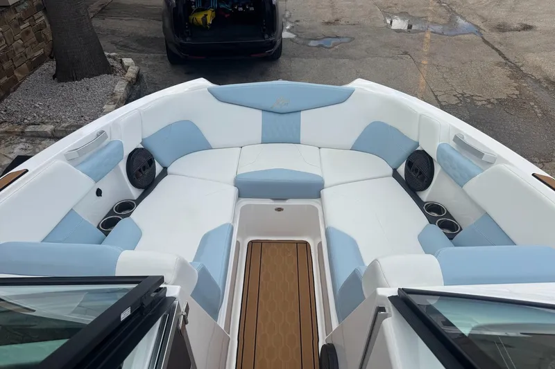 Slide: The Image of 2023 MasterCraft XT24 boat interior with white and blue seating, cup holders, and speakers. - 13