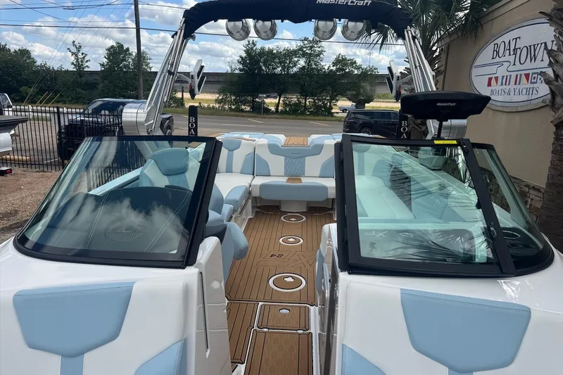 Slide: The Image of 2023 MasterCraft XT24 boat with blue and white interior, docked at Boat Town. - 14