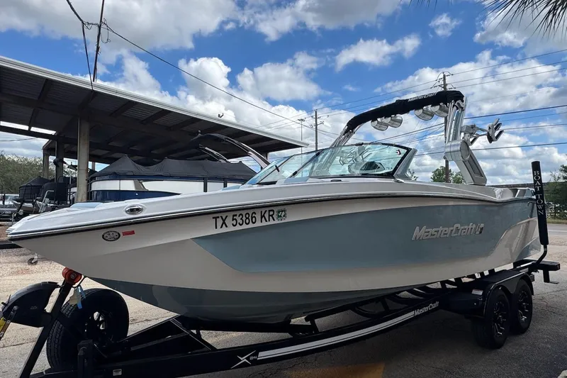 Slide: The Image of 2023 MasterCraft XT24 boat on trailer under blue sky. - 3