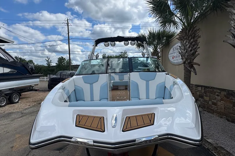 Slide: The Image of 2023 MasterCraft XT24 boat with blue and white interior, parked outdoors. - 4