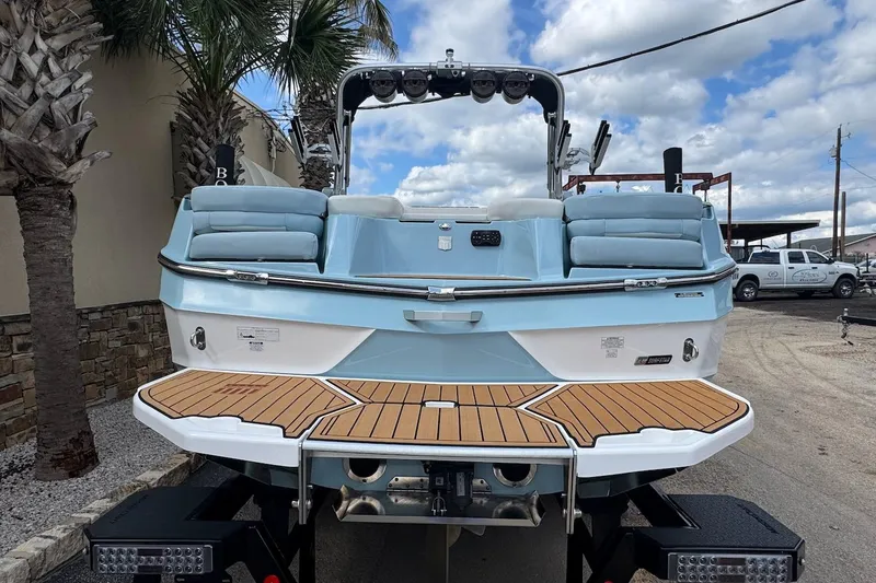 Slide: The Image of 2023 MasterCraft XT24 boat with teak deck, parked outdoors under cloudy sky. - 5
