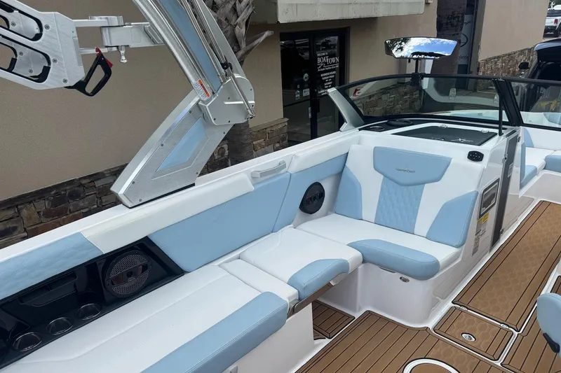 Slide: The Image of 2023 MasterCraft XT24 boat interior with blue and white seating and teak flooring. - 9