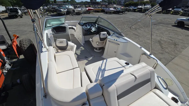 Slide: The Image of 2018 Chaparral 224 Sunesta boat interior with seating and steering wheel, parked outdoors. - 10