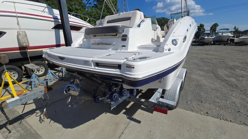 Slide: The Image of 2018 Chaparral 224 Sunesta boat on trailer, rear view, in a marina setting. - 2