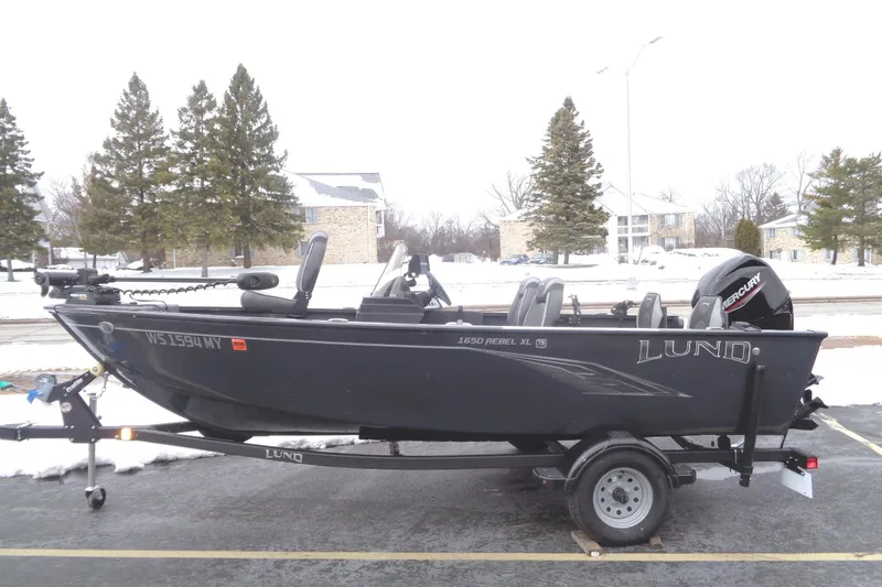 The Image of 2023 Lund 1650 Rebel XL SS fishing boat on trailer in snowy parking lot. - 0