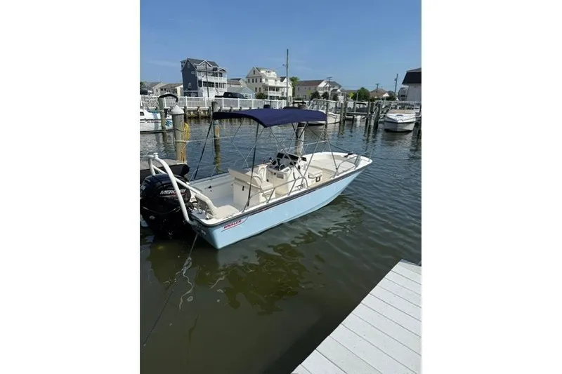 Slide: The Image of 2025 Boston Whaler 170 Montauk boat docked in a marina under clear blue skies. - 3