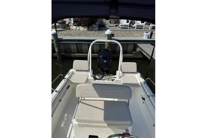 Slide: The Image of 2025 Boston Whaler 170 Montauk boat interior with seating and motor at dock. - 7
