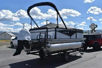Slide: The Image of 2025 Lowe LS 170 pontoon boat on trailer under a clear blue sky. - 10