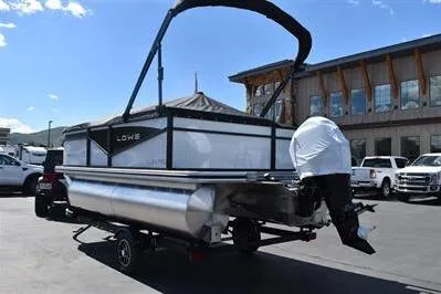 Slide: The Image of 2025 Lowe LS 170 pontoon boat with outboard motor, parked outdoors. - 11