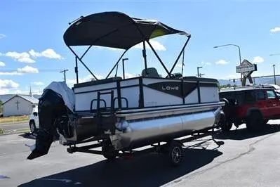 Slide: The Image of 2025 Lowe LS 170 pontoon boat on trailer, parked outdoors under clear sky. - 4