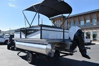 Slide: The Image of 2025 Lowe LS 170 pontoon boat with canopy, parked outdoors. - 5