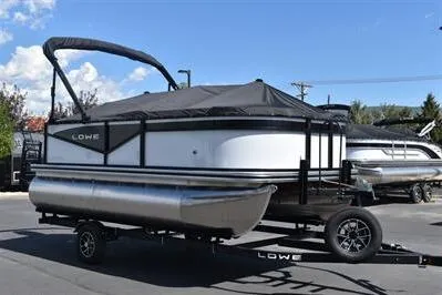 Slide: The Image of 2025 Lowe LS 170 pontoon boat on trailer, covered and parked outdoors. - 8