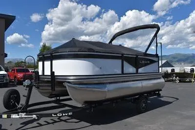 Slide: The Image of 2025 Lowe LS 170 pontoon boat on trailer under a blue sky. - 9