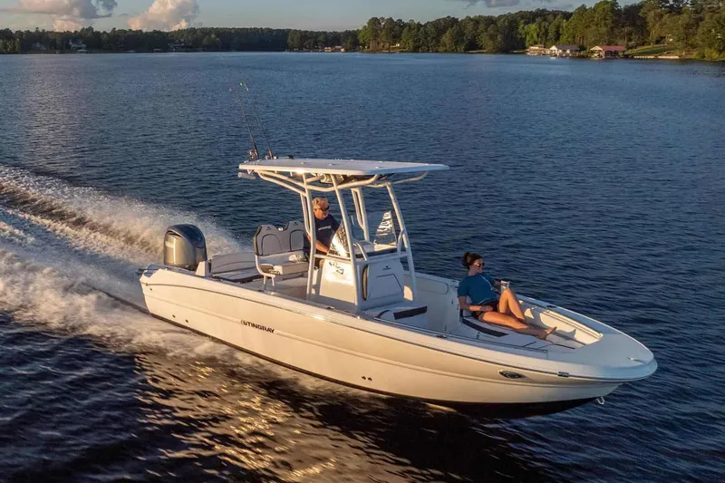 Slide: The Image of 2026 Stingray 236 CC boat cruising on a serene lake at sunset. - 15