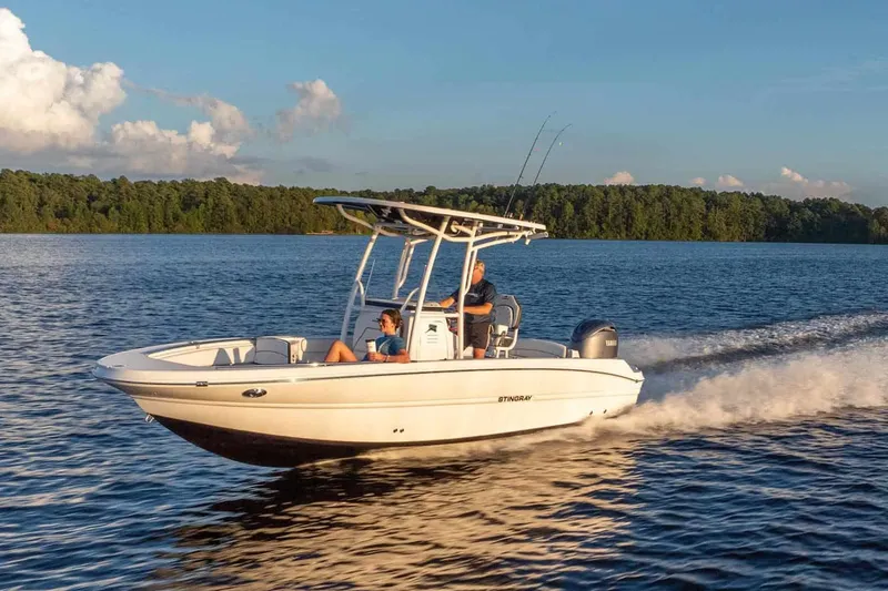 Slide: The Image of 2026 Stingray 236 CC boat cruising on a serene lake at sunset. - 16