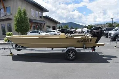 Slide: The Image of 2025 Lowe Roughneck 1860 boat on trailer, parked outdoors near buildings and mountains. - 4