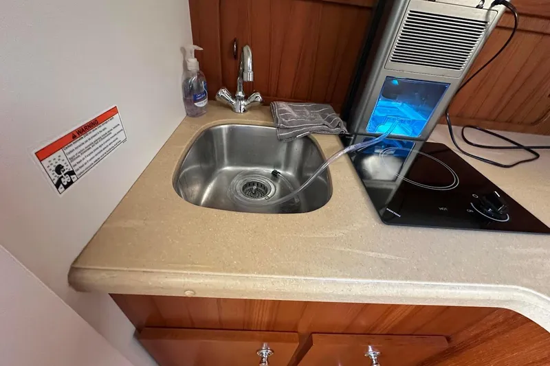 Slide: The Image of Compact kitchen area in a 2005 Tiara 2900 Open boat with sink and stove. - 11