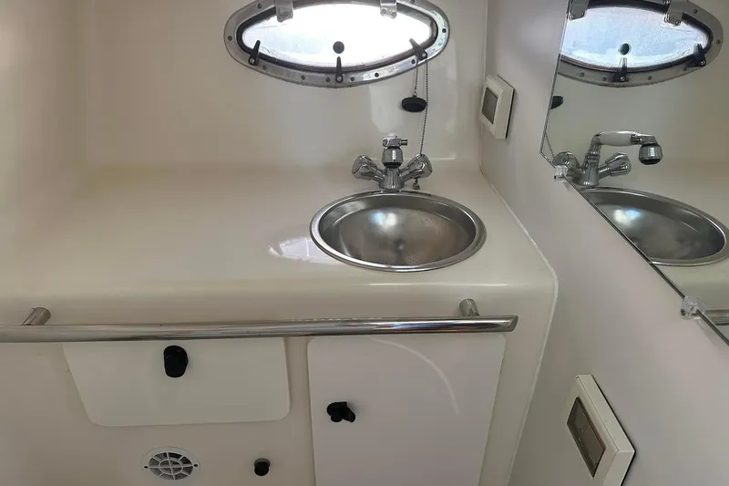 Slide: The Image of 2005 Tiara 2900 Open boat bathroom with sink, mirror, and porthole window. - 16
