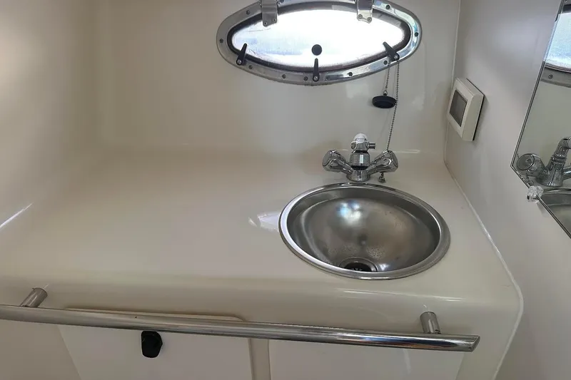 Slide: The Image of Compact sink area in 2005 Tiara 2900 Open boat, featuring stainless steel basin and porthole window. - 17