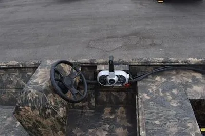 Slide: The Image of 2025 Lowe Roughneck 1860 Rambler boat interior with camouflage design and steering console. - 12