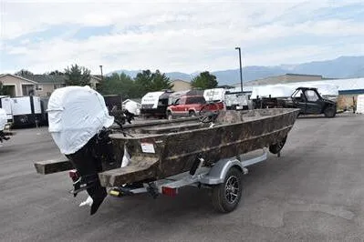 Slide: The Image of 2025 Lowe Roughneck 1860 Rambler boat on trailer, parked outdoors, with motor covered. - 4