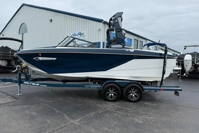 Slide: The Image of 2022 Nautique Super Air Nautique G21 boat on trailer, parked outside a marine dealership. - 2