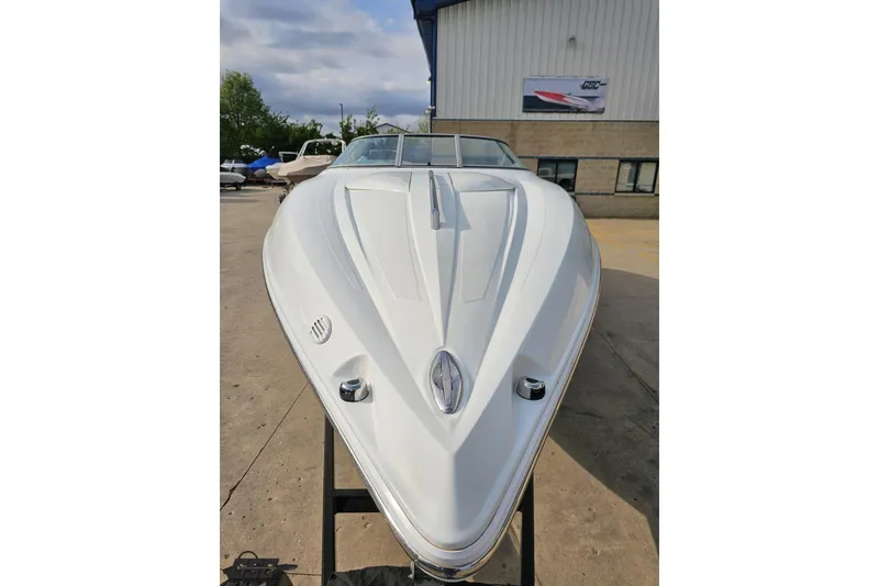 Slide: The Image of 2004 Baja 275 boat, sleek white design, docked outdoors under cloudy sky. - 13