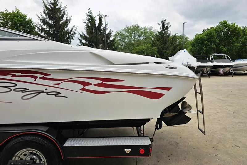 Slide: The Image of 2004 Baja 275 boat with red graphics on trailer, parked outdoors. - 24