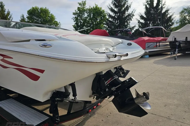Slide: The Image of 2004 Baja 275 boat with red accents, parked on a trailer in a marina. - 25