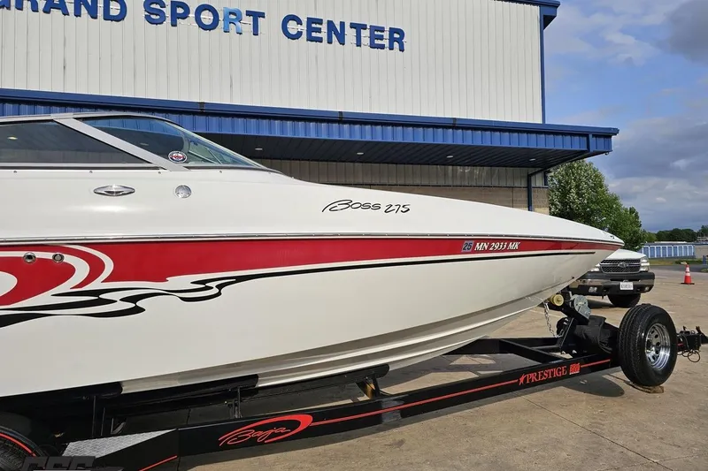 Slide: The Image of 2004 Baja 275 boat on trailer at dealership, featuring red and black graphics. - 4