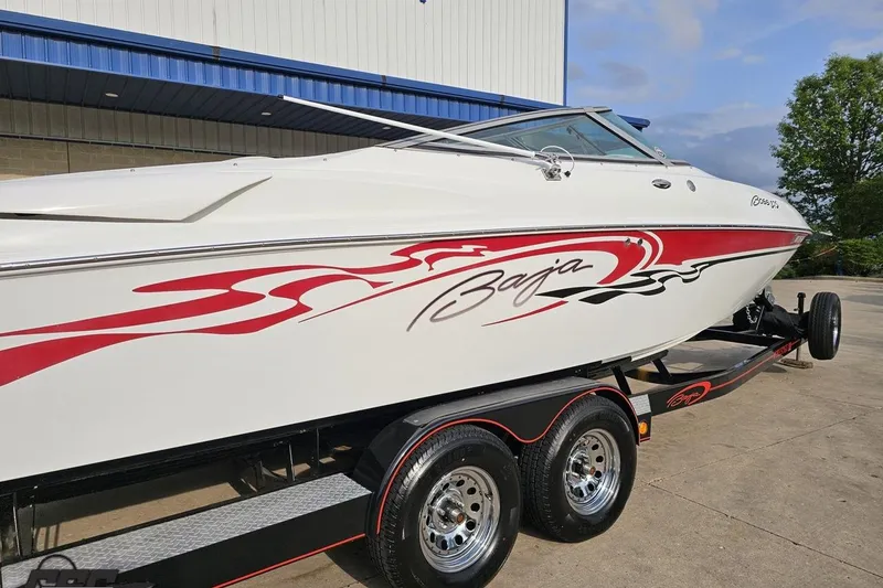 Slide: The Image of 2004 Baja 275 speedboat with red graphics on a trailer, parked outdoors. - 7