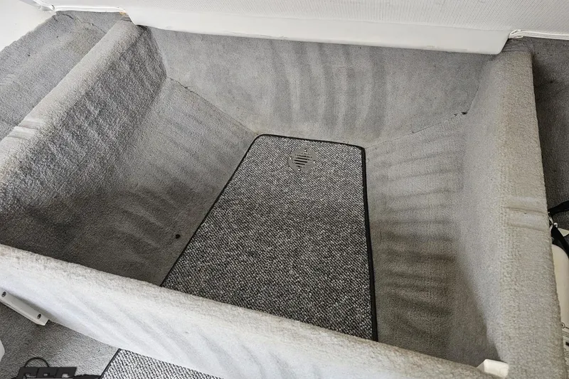 Slide: The Image of Interior storage compartment of a 2004 Baja 275 boat, featuring gray carpeting. - 73