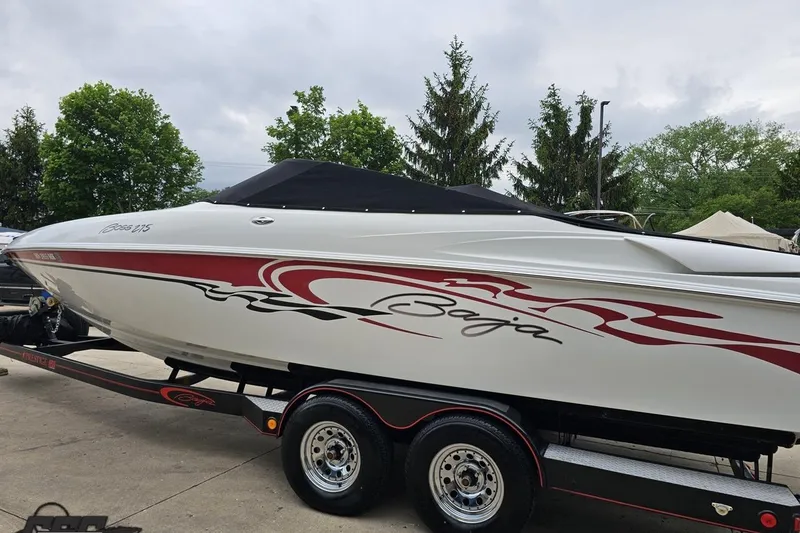 Slide: The Image of 2004 Baja 275 speedboat with red graphics on a trailer, parked outdoors. - 96
