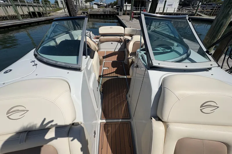 Slide: The Image of 2017 Crownline 275 SS boat interior with beige seating and wooden flooring at a dock. - 14