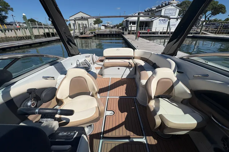 Slide: The Image of 2017 Crownline 275 SS boat interior with luxurious seating and wood flooring at a dock. - 17