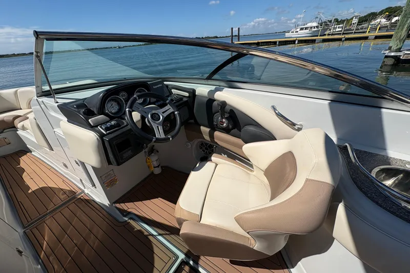 Slide: The Image of 2017 Crownline 275 SS boat interior with steering wheel and seating, docked by the water. - 18